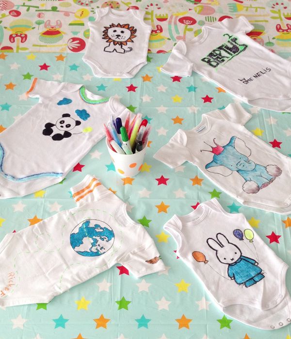 Witte rompertjes versierd met textielstiften tijdens een babyshower